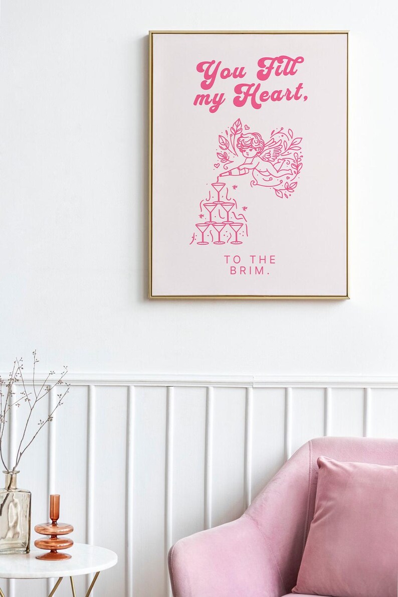 May include: Pink and white framed print with a pink illustration of a cupid pouring champagne into a pyramid of glasses. The text reads "You fill my heart, to the brim."
