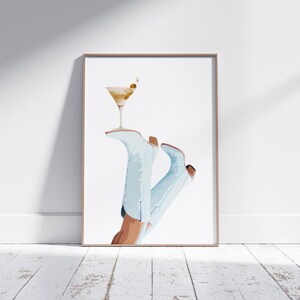 May include: A watercolor illustration of a pair of light blue cowboy boots with a martini glass resting on top. The martini glass is filled with a light yellow liquid and has a green olive garnish.