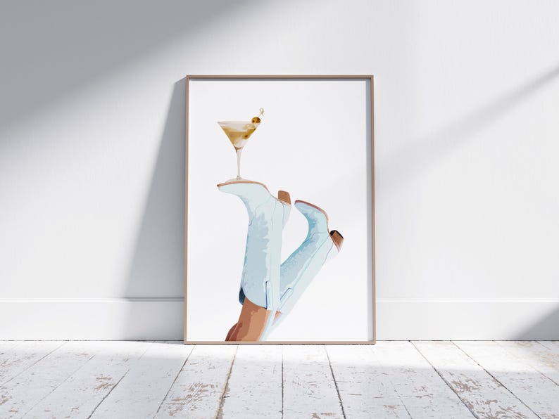 May include: A watercolor illustration of a pair of light blue cowboy boots with a martini glass resting on top. The martini glass is filled with a light yellow liquid and has a green olive garnish.