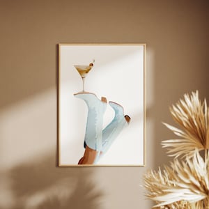 May include: A watercolor illustration of a pair of light blue cowboy boots with a martini glass resting on top. The martini glass is filled with a light yellow liquid and has a green olive garnish.