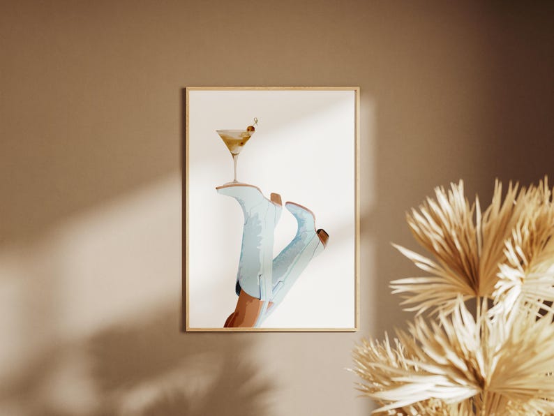 May include: A watercolor illustration of a pair of light blue cowboy boots with a martini glass resting on top. The martini glass is filled with a light yellow liquid and has a green olive garnish.