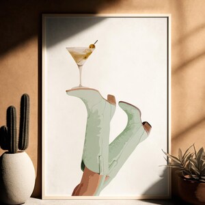 Pu&ograve; includere: Un'illustrazione digitale di un paio di stivali da cowboy verdi con un bicchiere da martini in cima. Gli stivali sono in posizione rialzata, come se stessero tenendo il bicchiere.