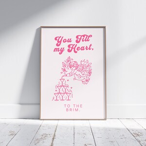 May include: Pink and white printable art print with a graphic of a cherub pouring champagne into a stack of glasses. The text reads "You fill my heart, to the brim."