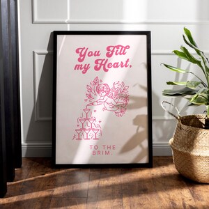 May include: A pink and white poster with a graphic of a cupid pouring a drink into a stack of glasses. The text on the poster reads "You fill my heart, to the brim."