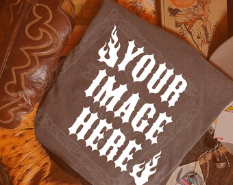 May include: A dark grey t-shirt with the text "YOUR IMAGE HERE" in white, stylised lettering. The shirt is displayed with brown cowboy boots, a vintage book, and other western-themed accessories.