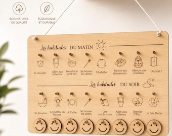 May include: Wooden Montessori routine board with the text "TABLEAU ROUTINES MONTESSORI". It features morning and evening habit icons, smiley face tokens, and text in French. The board is designed to help children gain autonomy.