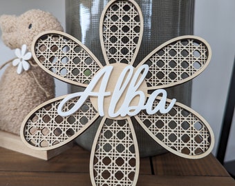 May include: A wooden flower with a woven pattern and the name "Alba" written in white on the center. The flower is light brown and has a natural wood finish.