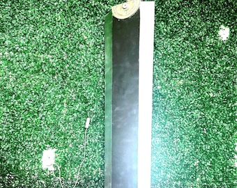 May include: A large, rectangular, double-edged sword featuring a dark central panel with metallic silver edges. The hilt is white with a semi-circular metallic guard at the base of the blade. The design is flat and wide, resembling a heavy fantasy weapon.