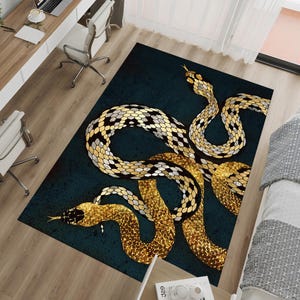 May include: A rectangular rug with a design of three golden snakes on a dark teal background. The snakes have detailed patterns in gold, black, and white, with their bodies intertwined. The rug is placed on a wooden floor. The rug's dimensions are in centimetres.