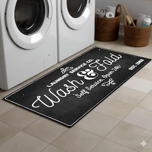 May include: Black rectangular laundry room mat with white text that reads "Wash & Fold" and "Laundry Service Co. Self Service, Open 24h". The mat has a chalkboard-like appearance and the year "EST. 1962" is printed on the right side.