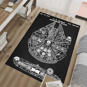 Puede incluir: Alfombra rectangular negra con un plano blanco detallado de la nave espacial Halcón Milenario. La alfombra incluye el texto "Apr. 19, 1979 U.S. Patent MILLENNIUM FALCON Des. 228,688". El diseño es un dibujo técnico detallado.