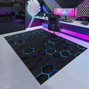 May include: A black area rug with a 3D hexagonal pattern and blue neon accents. The rug is in a gaming room setting, with a gaming chair and desk visible in the background.