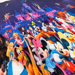 May include: A colourful textile featuring a collage of Disney characters. The design includes Mickey and Minnie Mouse, princesses, and other iconic figures, set against a backdrop of a castle and a starry sky.