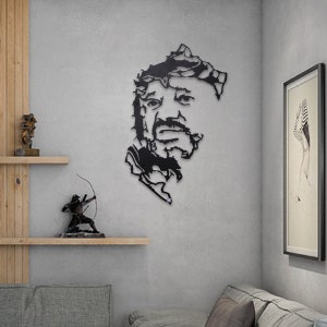 May include: Black metal wall art featuring a stylized portrait of a man with a beard. The art is cut out in a jagged, abstract style.