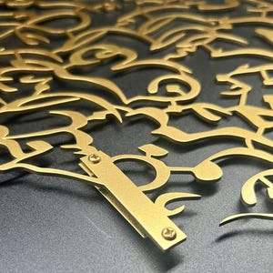 K&ouml;nnte beinhalten: Ein Wandkunstwerk aus goldenem Metall mit einem filigranen, komplizierten Design aus wirbelnden &Auml;sten und Bl&auml;ttern. Das St&uuml;ck ist mit Schrauben an der Wand befestigt.