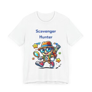 Puede incluir: Camiseta blanca con una ilustración de dibujos animados de un cazador de tesoros que lleva un sombrero, gafas de sol y una mochila. El texto "Scavenger Hunter" está impreso en azul sobre la ilustración.