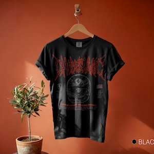 May include: A black short-sleeve t-shirt featuring a red graphic of a racing helmet and the text Charles Leclerc and Monegasque Racing Prince. The shirt has a crew neckline and rolled sleeves, displayed on a wooden hanger against a solid wall.
