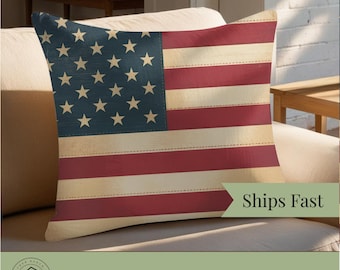 Könnte beinhalten: Ein quadratisches Kissen mit einem verwitterten Design der amerikanischen Flagge. Das Kissen hat ein blaues Quadrat mit weißen Sternen in der oberen linken Ecke und rot-weißen Streifen. Die Worte "Ships Fast" stehen auf einem grünen Banner.