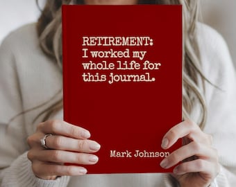 May include: A red journal with the text "RETIREMENT: I worked my whole life for this journal." and the name "Mark Johnson" printed in white. The journal is held by a person.