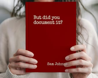 May include: A red book with the text "But did you document it?" and the author's name "Sam Johns" in white. The book is held by a person wearing a cream-colored sweater.