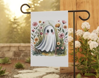 May include: A white garden flag featuring a friendly ghost illustration surrounded by colorful flowers. The ghost has large, round eyes and a gentle expression. The flag is displayed on a black metal garden stake, perfect for outdoor decor.
