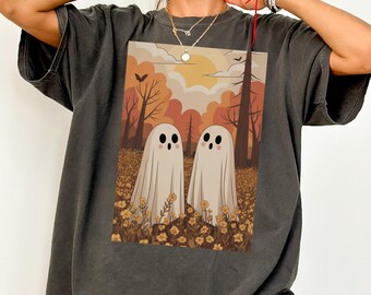 May include: Dark gray t-shirt featuring a whimsical illustration of two friendly ghosts in a field of yellow flowers, set against a backdrop of an autumn forest with a sunset and bare trees. The design is printed on a comfortable, oversized tee.
