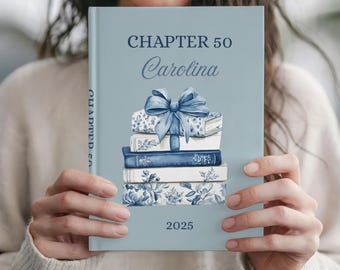 May include: A light blue book with the text "CHAPTER 50 Carolina 2025". The cover features a stack of books with a blue bow on top. The books have floral and patterned designs in shades of blue.