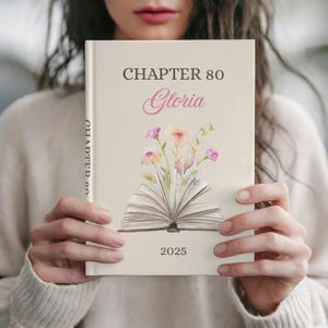 May include: A cream-coloured book with the text "CHAPTER 80 Gloria 2025" and an illustration of an open book with flowers. The book's spine reads "CHAPTER 80". The cover features a floral design in pink, yellow, and purple.