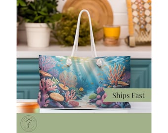 Puede incluir: Un bolso tote con una vibrante escena submarina que muestra arrecifes de coral, peces y luz solar. Tiene asas de cuerda blanca. El texto "Ships Fast" es visible.