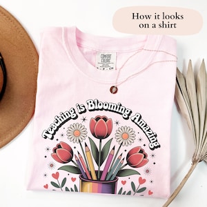 May include: Pink t-shirt with a retro-style graphic that says "Teaching is Blooming Amazing" with flowers, pencils, and hearts.
