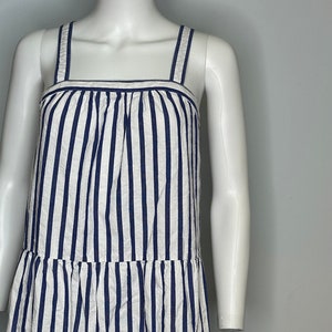 May include: A white and blue striped sleeveless dress with a square neckline and a tiered skirt.