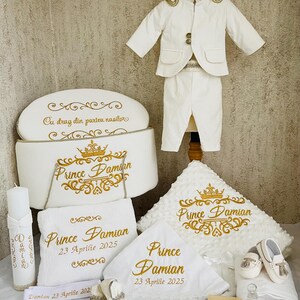 Pode incluir: Conjunto de batismo branco para bebé com bordados dourados. O conjunto inclui um fato, chapéu, manta, toalhas, sapatos e uma caixa. O texto "Prince Damian" e a data "23 Aprilie 2025" estão bordados.