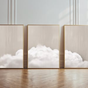 Puede incluir: Tres impresiones enmarcadas con un diseño minimalista que presenta una formación de nubes blancas sobre un fondo beige claro.