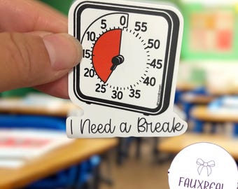 May include: A white sticker with a black border featuring a timer design. The timer shows a red section and the text "I Need a Break". The sticker is held in a hand.