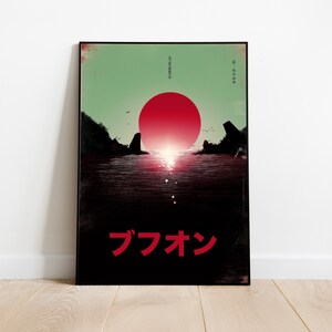 以下が含まれることがあります： 水面に沈む赤い太陽を描いた額入りアートプリント。暗い陸地と鳥のシルエット。空は淡い緑色で、上下に日本語のテキストがあります。「ブフォン」という言葉は赤色です。