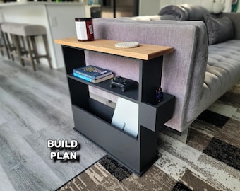 May include: A black and wood side table with shelves and a magazine rack. The top shelf holds a candle, coaster, and a book. A video game controller and a small figurine are on the middle shelf. The text "BUILD PLAN" is visible.
