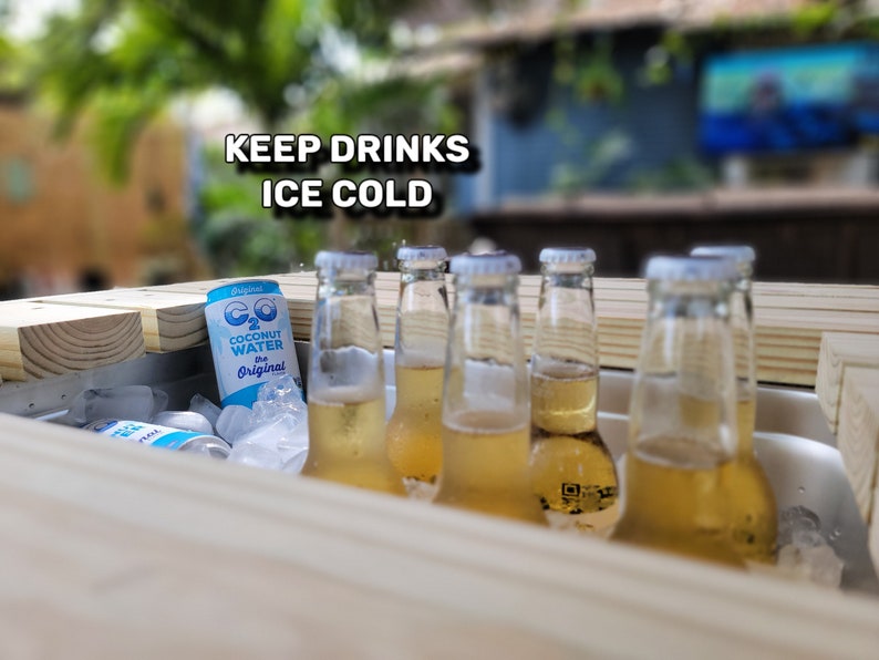 K&ouml;nnte beinhalten: Ein Holz-K&uuml;hlbox mit Eis und mehreren Flaschen eines hellgelben Getr&auml;nks. Die K&uuml;hlbox hat ein Schild mit der Aufschrift "KEEP DRINKS ICE COLD". Eine der Flaschen hat ein Etikett mit der Aufschrift "CO2 Coconut Water The Original".