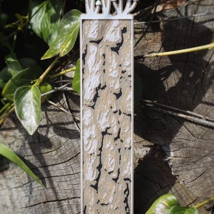 This bookmark displays a textured pattern resembling cracked tree bark, in shades of brown, beige, and black. Mushrooms appear to be growing from the top of the bookmark.
