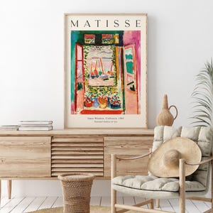 May include: A poster featuring a painting by Henri Matisse titled "Open Window, Collioure, 1905". The painting depicts a colorful view of a harbor with boats through an open window. The poster includes the artist's name, the painting's title, and the year it was created.
