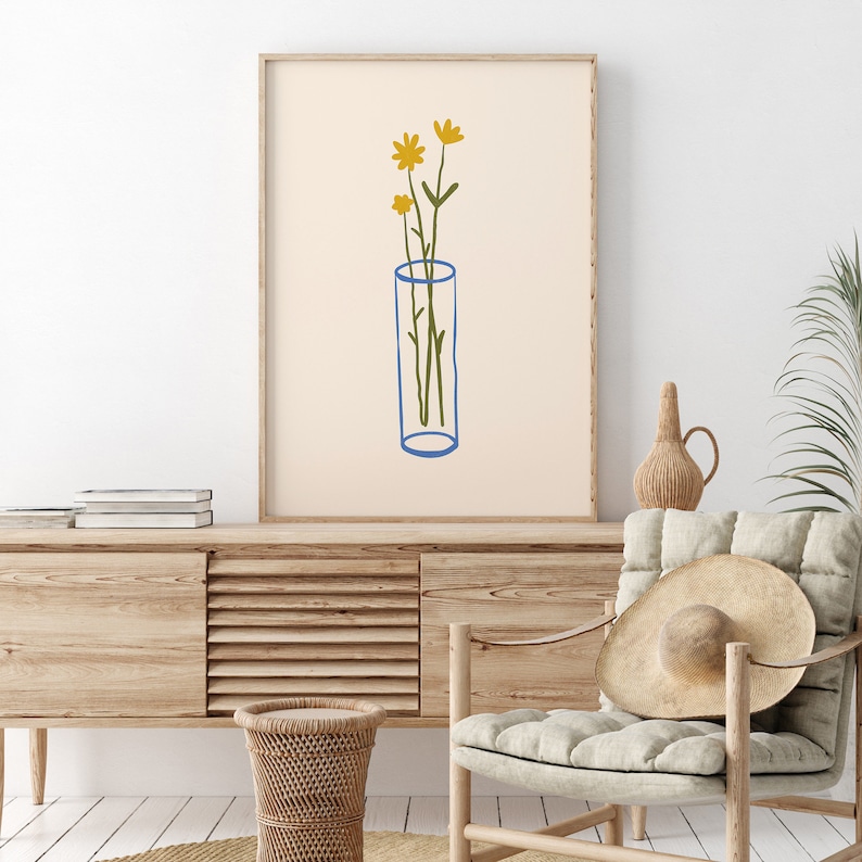 Puede incluir: Una impresi&oacute;n de arte minimalista que presenta un dibujo lineal simple de un jarr&oacute;n con tres flores amarillas. El jarr&oacute;n es azul y el fondo es de color beige claro.