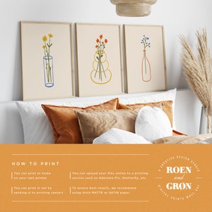 Puede incluir: Tres impresiones florales minimalistas en marcos, con dibujos lineales simples de flores en jarrones. Las impresiones se muestran en una cama con almohadas naranjas y blancas. El texto "HOW TO PRINT" y "ROEN and GR&Oslash;N" es visible debajo de las impresiones.