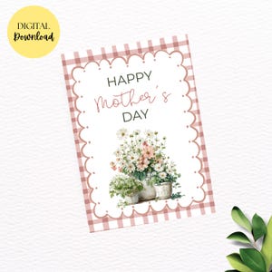 Puede incluir: Una tarjeta de descarga digital con un borde de cuadros rosa y bordes festoneados. La tarjeta dice "HAPPY Mother's DAY" en escritura negra y rosa. Flores de acuarela en blanco y rosa están en tres macetas pequeñas. Un círculo amarillo con "DIGITAL Download" está en la esquina superior izquierda.