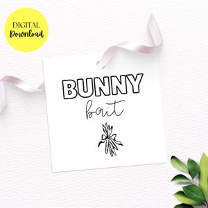 May include: White square tag with the words "BUNNY bait" in black, with a carrot illustration. A yellow circle with "DIGITAL Download" is in the upper left. A pink ribbon is attached to the tag.
