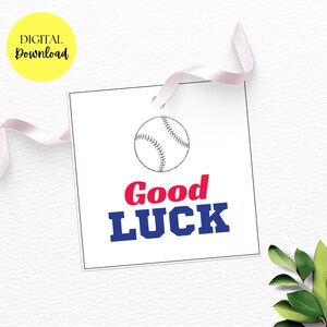 May include: A white square tag with a baseball illustration and the words "Good Luck" in red and blue. The tag has a small gold grommet and a white ribbon. A yellow circle with "DIGITAL Download" is in the upper left corner.
