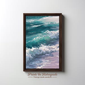 Puede incluir: Pintura al óleo enmarcada que representa olas del océano en tonos turquesa y blanco, con toques de rosa en la parte inferior. La obra de arte está en un marco de madera marrón oscuro. El texto "Prints In Retrograde - Vintage made modern" está en la parte inferior.