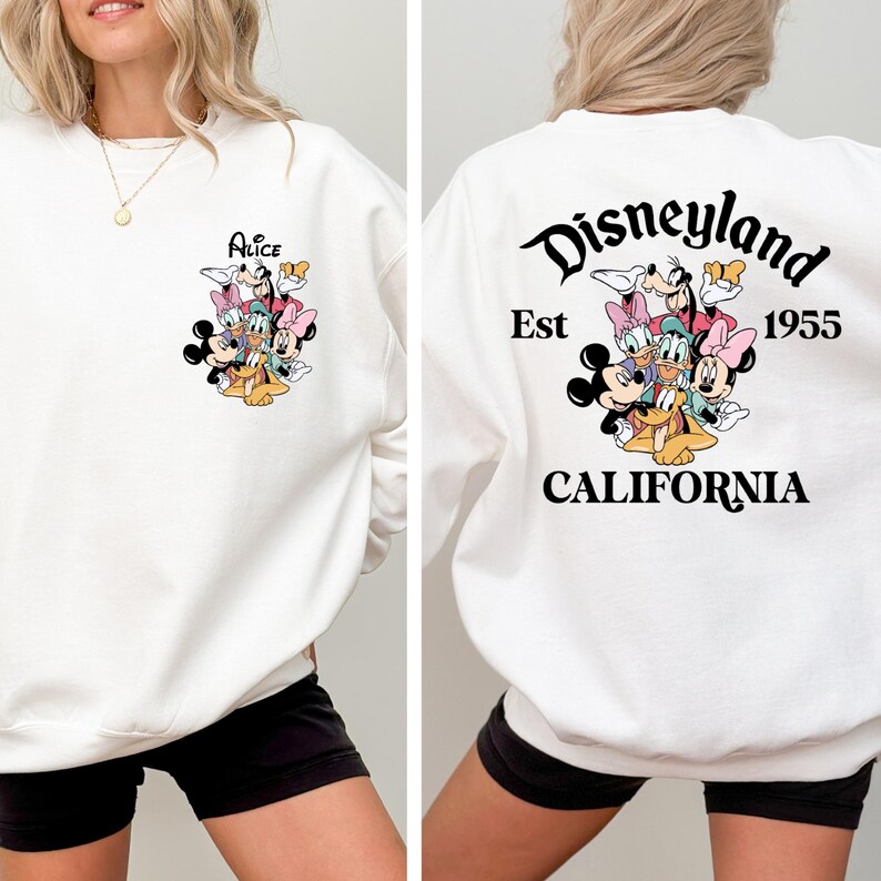 May include: White sweatshirt featuring a colorful graphic of Disney characters on the front and back. The front displays the name "Alice" above the characters. The back of the sweatshirt says "Disneyland Est 1955 California".