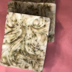 May include: Three bars of handmade soap with a white base and green swirls. The soap has a speckled appearance with small green flecks throughout.
