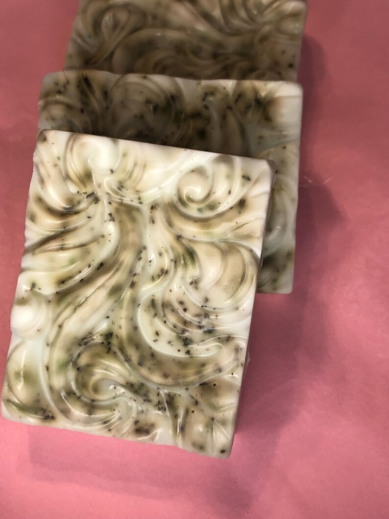 May include: Three bars of handmade soap with a white base and green swirls. The soap has a speckled appearance with small green flecks throughout.