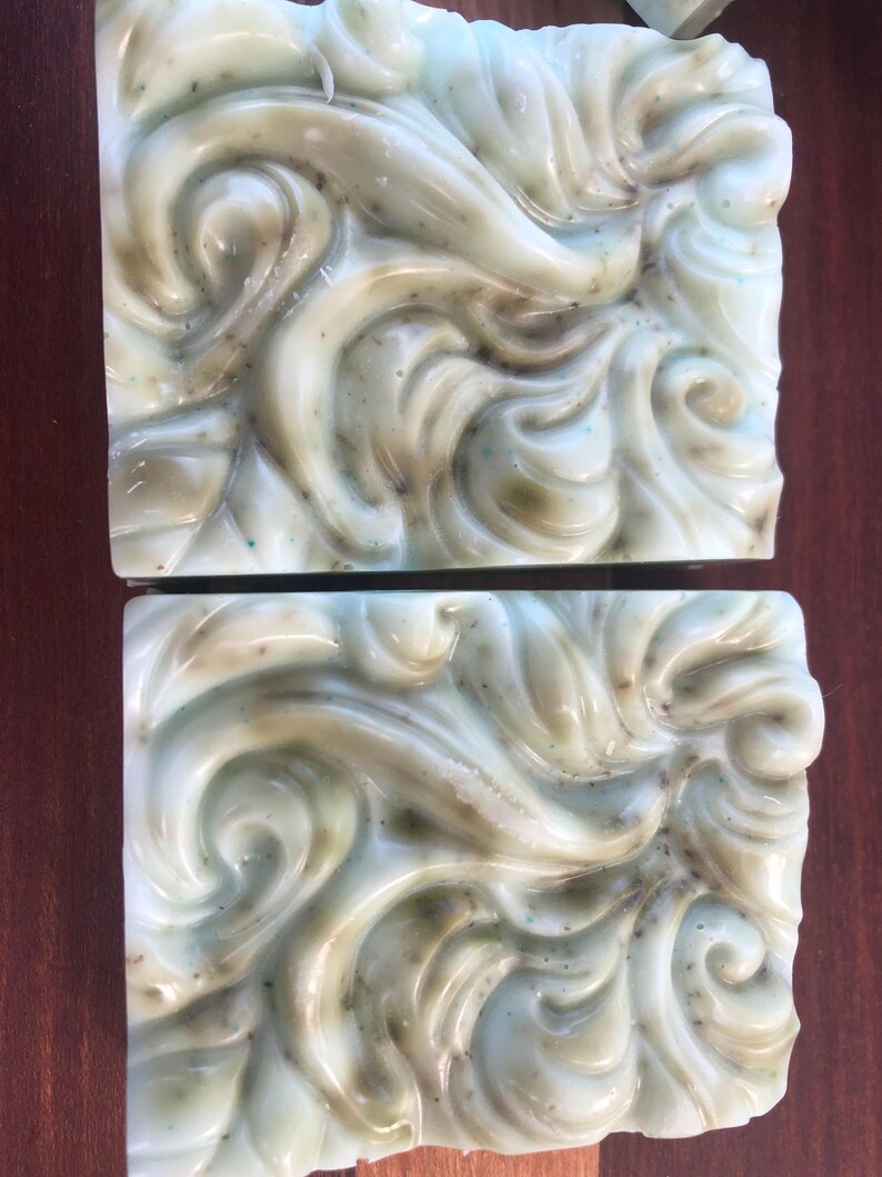May include: Two bars of handmade soap with a swirling green and white design. The soap has a marbled appearance.