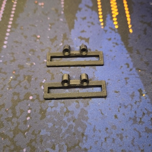 May include: Two black plastic rectangular pieces with two small round holes on each piece.